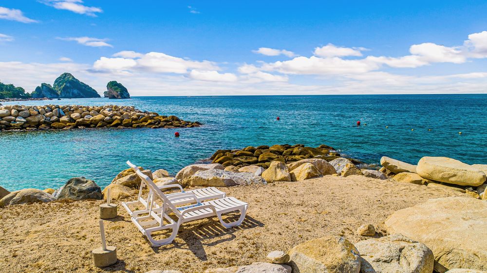 Loungers at the Sierra del Mar Beach Club with Los Arcos in the distance